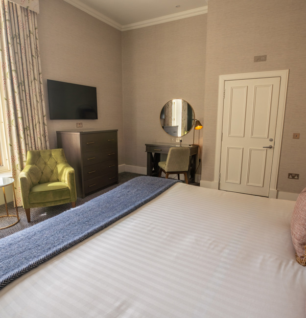 Guest Double room with king-sized bed, dresser, TV, two chairs, and a window.