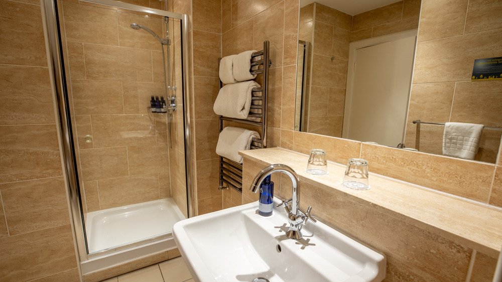 Bathroom with sink, shower, and towel rack.