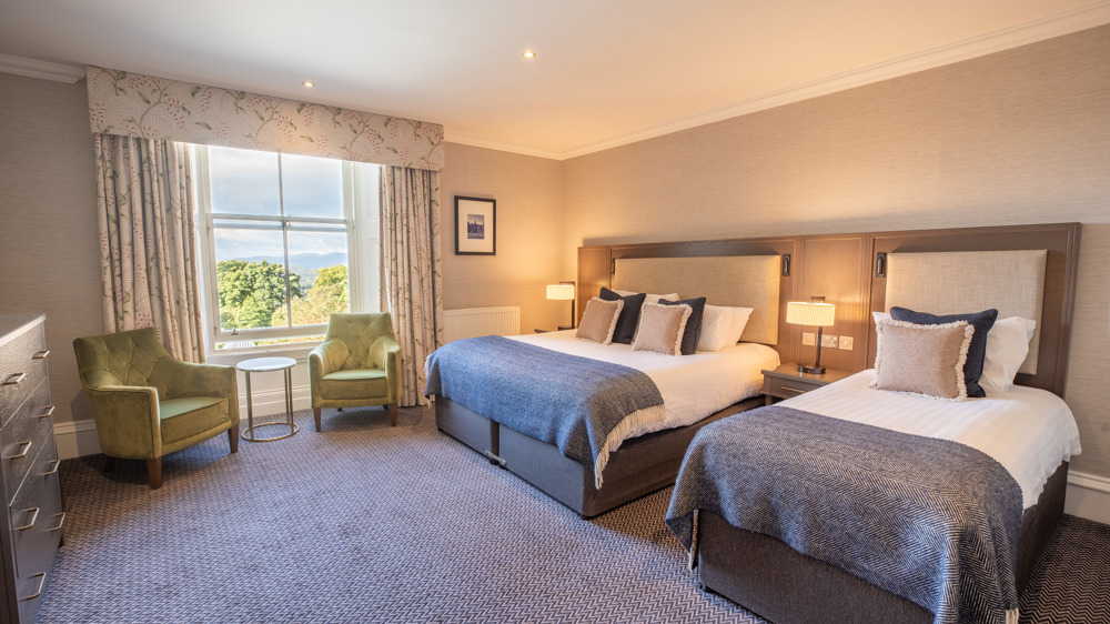 Feature Family Room with a king-sized bed, single bed, two chairs next to a window and extra floor space.