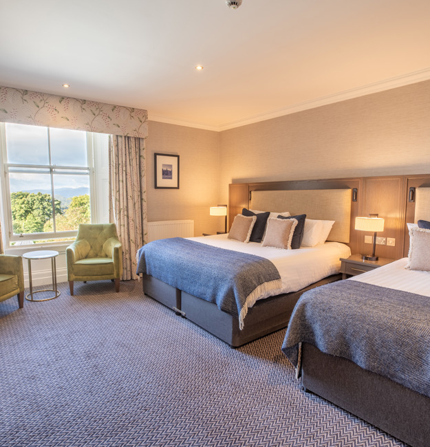 Feature Family Room with a king-sized bed, single bed, two chairs next to a window and extra floor space.