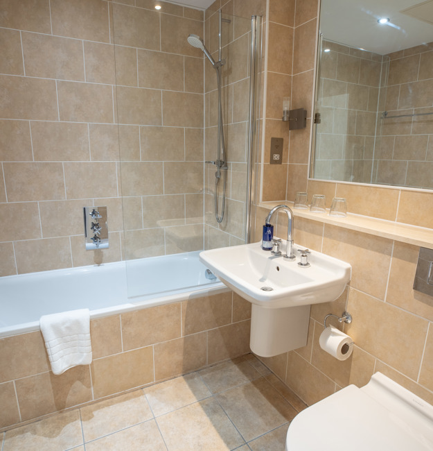 Bathroom with shower over bath, sink, toilet, and mirror.