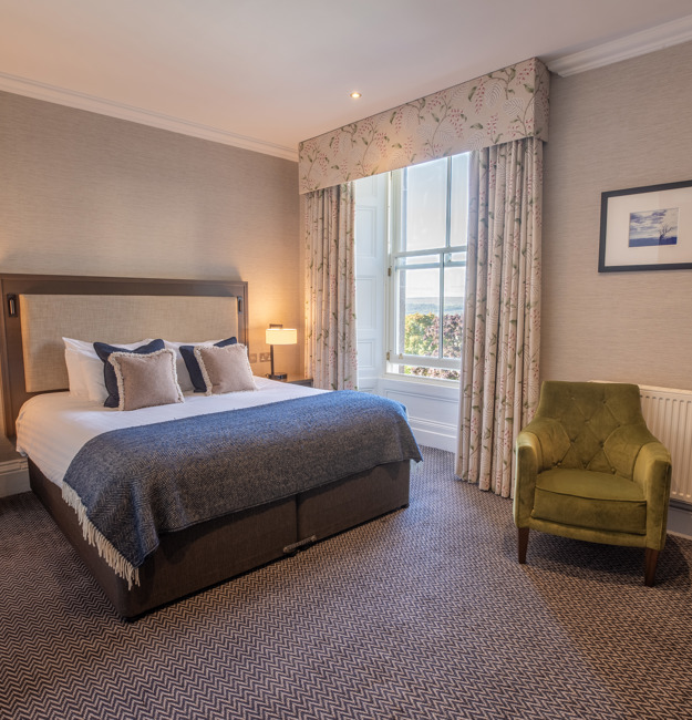 King-sized bed, bedside table, two chairs and a window