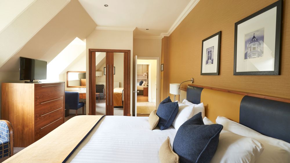 Family apartment with king-sized bed, dresser, TV. You can see the other sleeping area in the background.