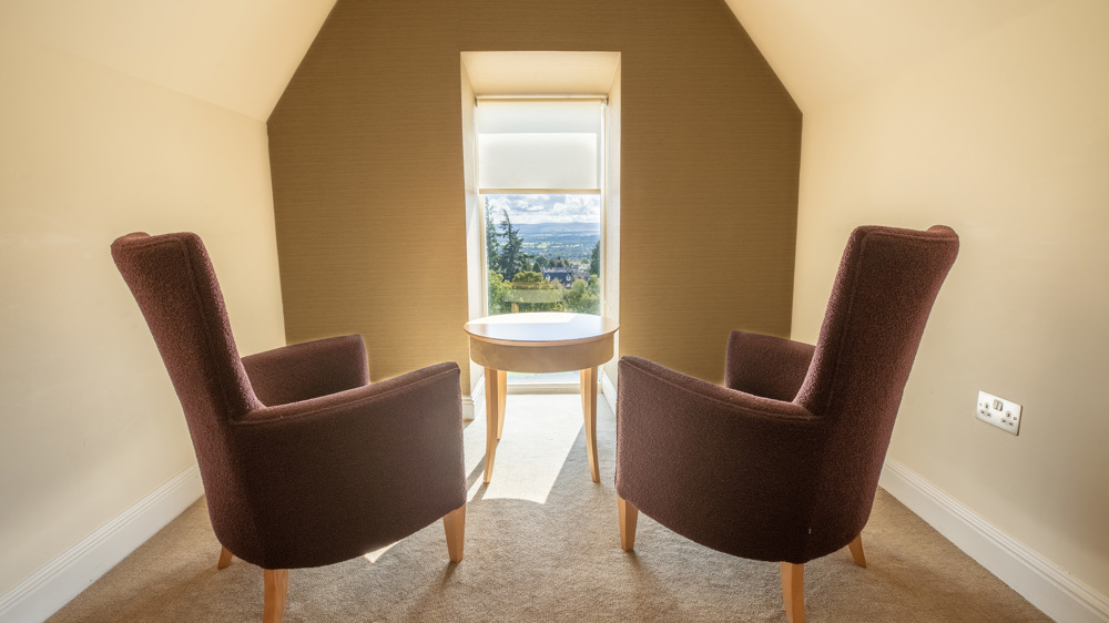 Two chairs in front of a window with a bright, sunny view