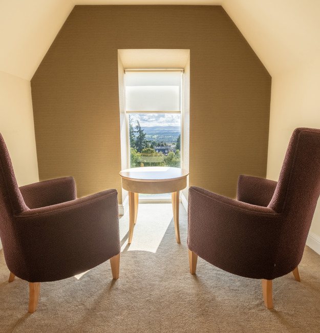Two chairs in front of a window with a bright, sunny view