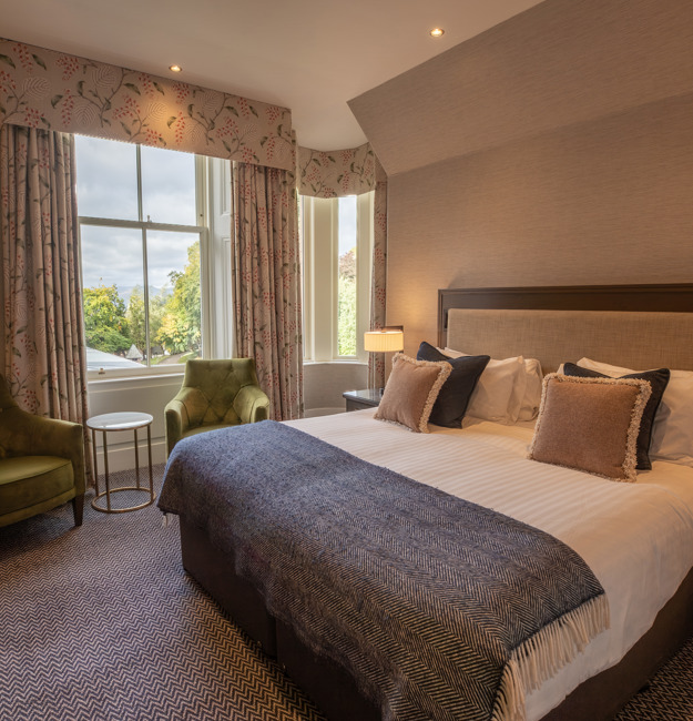 Guest Double room with king-sized bed, bedside table, two chairs, and a window.