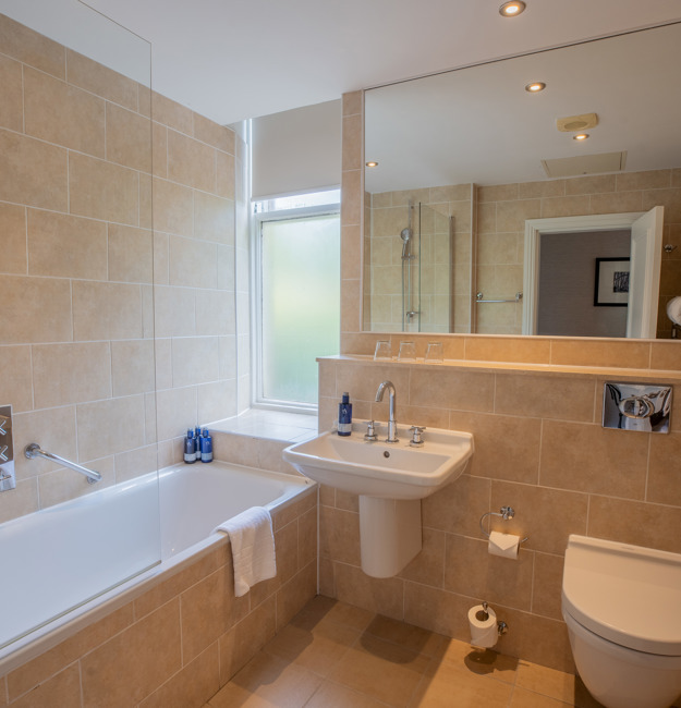 Bathroom with a bathtub, a sink, a mirror, and a toilet.