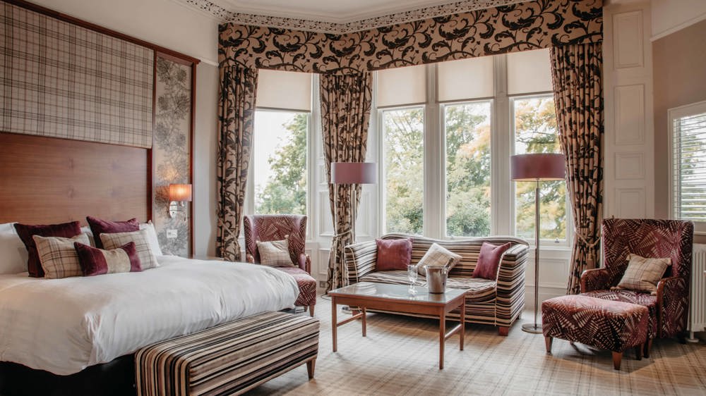 Leigh signature double with king-sized bed, two chairs and a loveseat in front of a bay window.