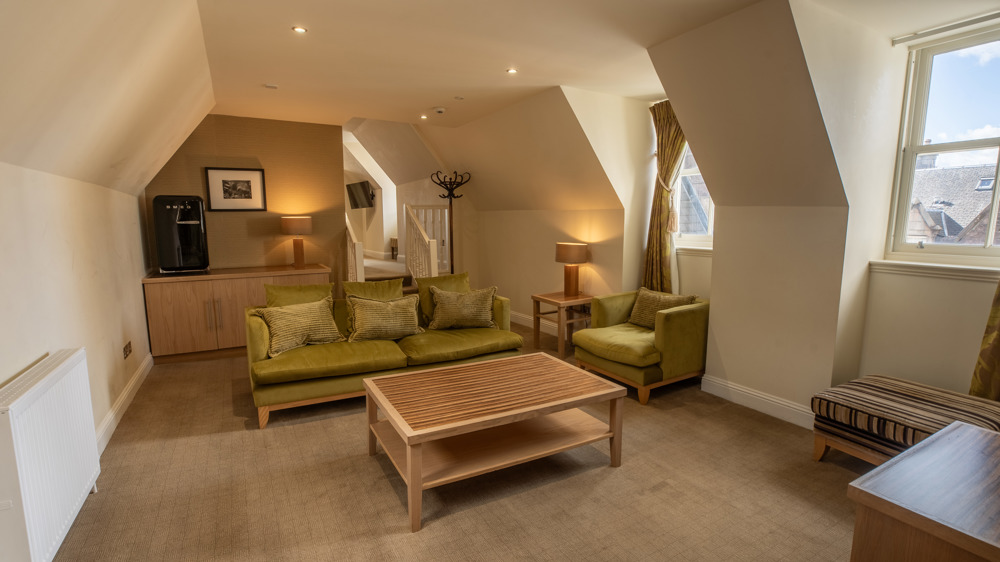 Signature suite living area with a sofa, chair, coffee table and Smeg fridge.