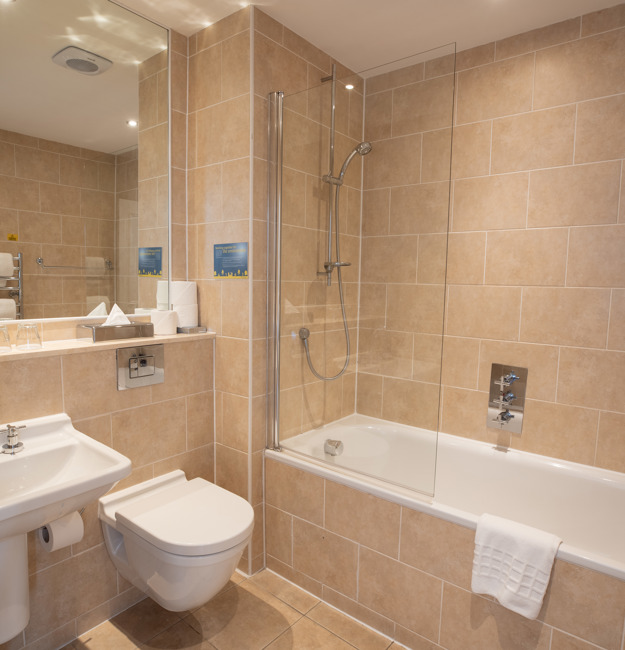 Bathroom with shower over bath, toilet, sink and mirror