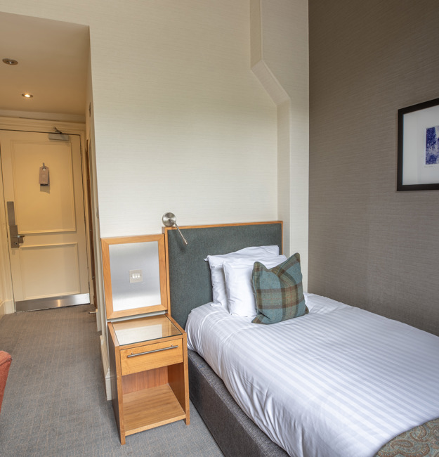 Guest single room with single bed, bedside table, and desk.